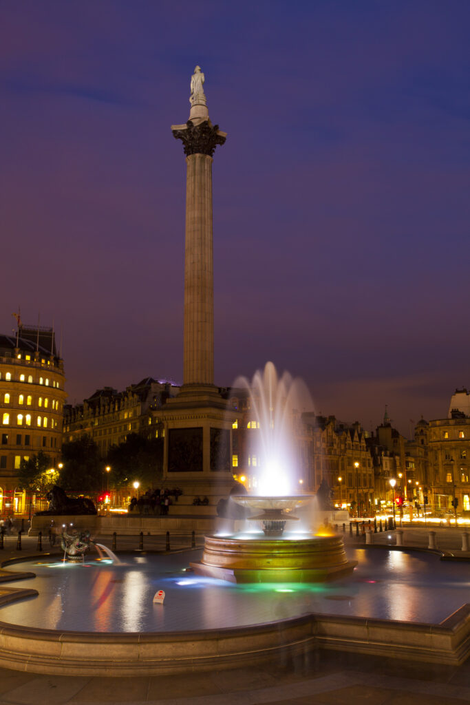 England, Greater London, City of Westminster. Nelson’s Column and nearby fountains in Trafalgar Square, a popular tourist destination in London, photographed at dusk.