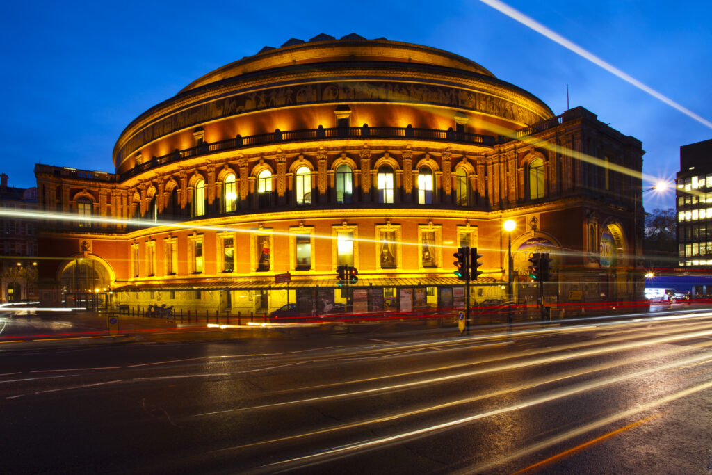 England, London, The Royal Borough of Kensington and Chelsea, The Royal Albert Hall. Busy traffic in front of the Royal Albert Hall, viewed at dusk.