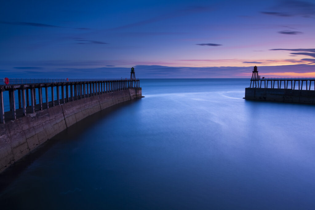 England, North Yorkshire, Whitby. The entrance piers of Whitby Harbour at dawn.