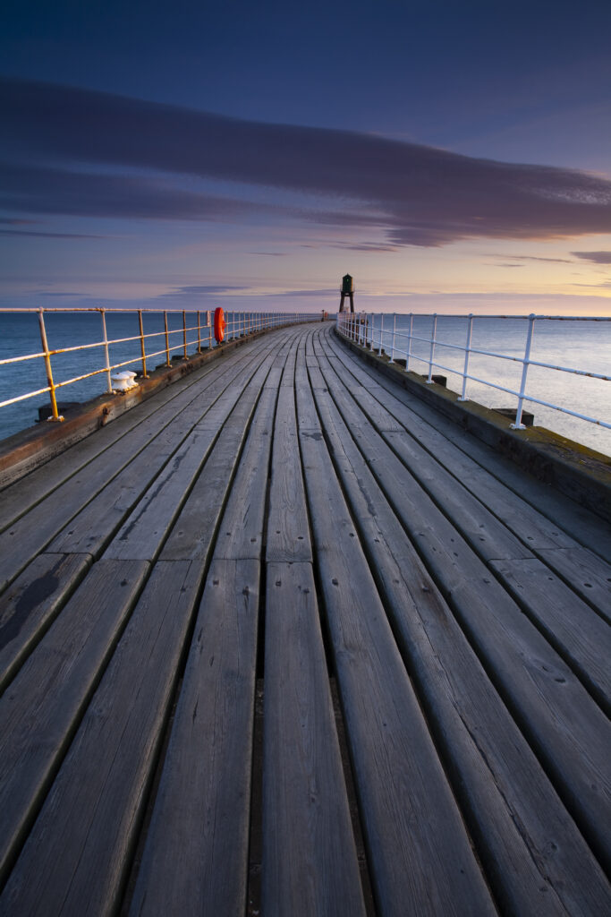 England, North Yorkshire, Whitby. One of the entrance piers of Whitby Harbour at dawn.