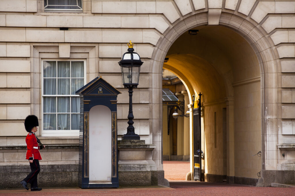 England, Greater London, City of Westminster. Queens' Guard walking towards archway outside Buckingham Palace.