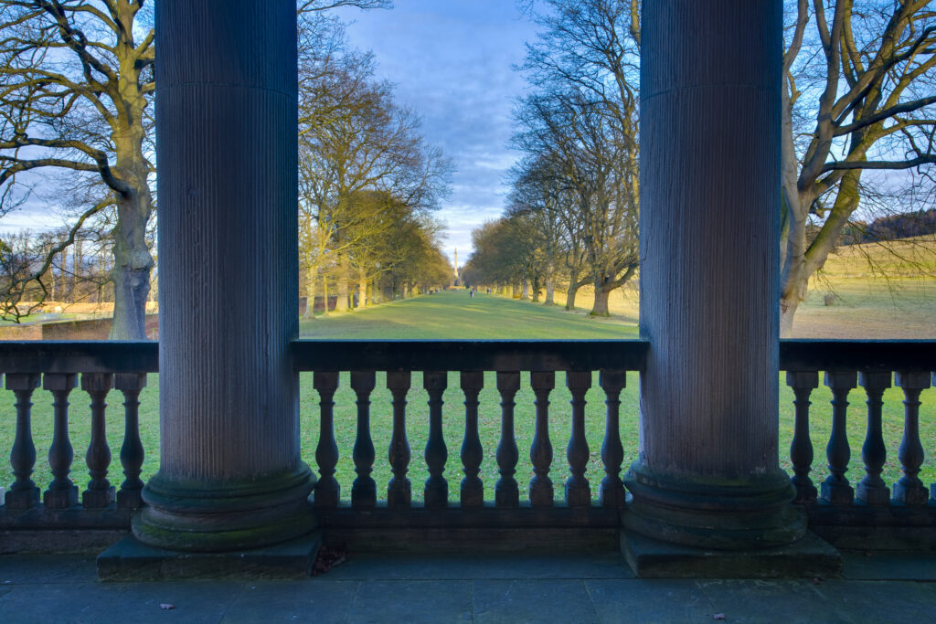 England, Tyne and Wear, Gibside. Looking through the stone pillars of the Gibside Chapel towards the half mile, Oak tree lined walk heading to the Column of Liberty.