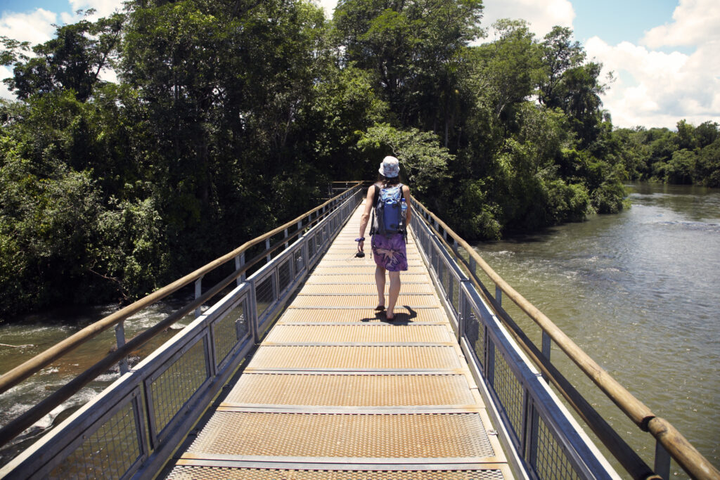 Argentina, Misiones, Iguazu National Park. Girl crossing a bridge over a river near the Iguazu waterfalls - A world heritage site.