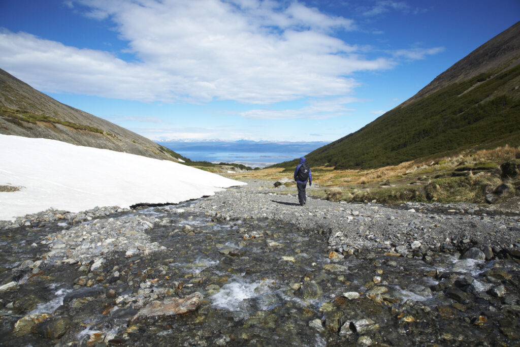 Argentina, Tierra Del Fuego, Ushuaia. Hiker walking along a steam running through a mountain valley near Ushuaia.