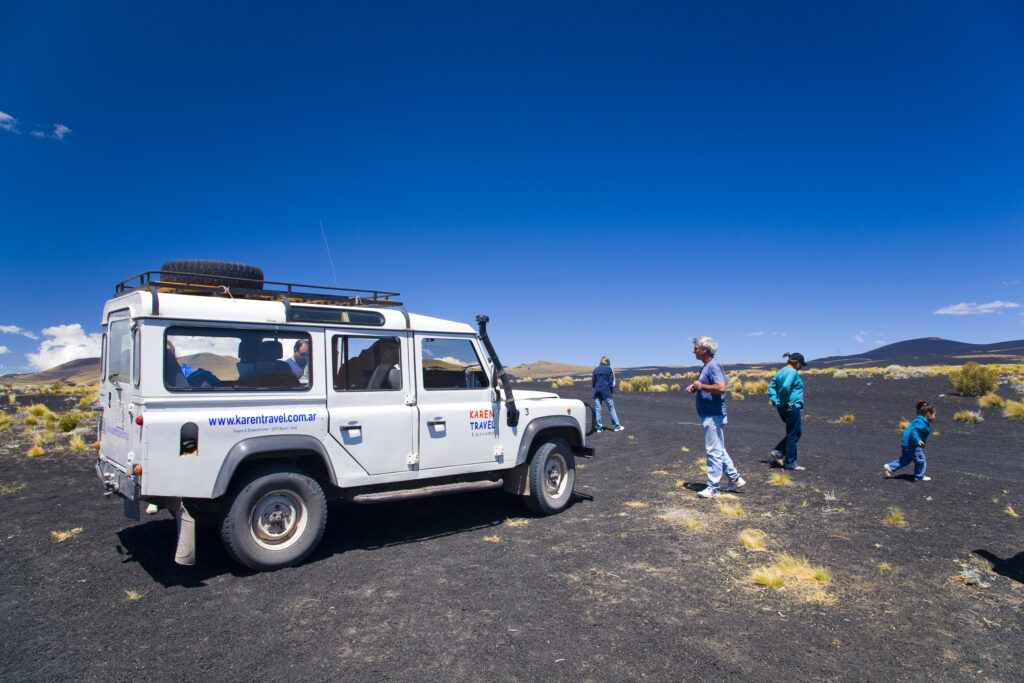 Argentina, Mendoza, Parque Provincial Payunia. Tourists and 4 wheel drive jeep exploring the reserve.