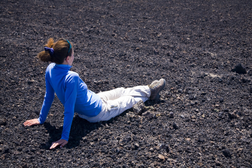 Argentina, Mendoza, Parque Provincial Payunia. Tourist resting on the volcanic black sands of the reserve.