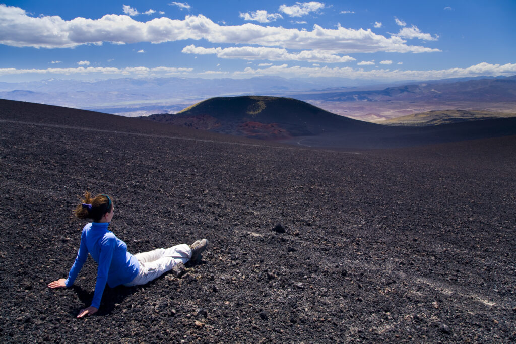Argentina, Mendoza, Parque Provincial Payunia. Tourist resting on the volcanic black sands of the reserve.