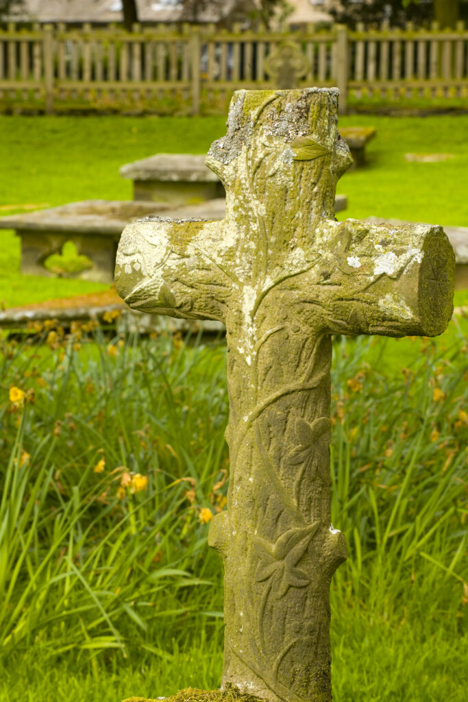 England, Yorkshire, Yorkshire Dales National Park. Stone cross styled as a wooden cross in the grounds of Bolton Abbey.