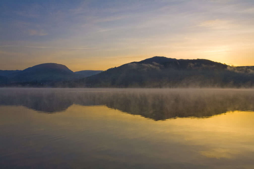 England, Cumbria, Lake District National Park. Dawn at Low Wray, looking across the still waters of Windermere, the largest lake to be found in England.