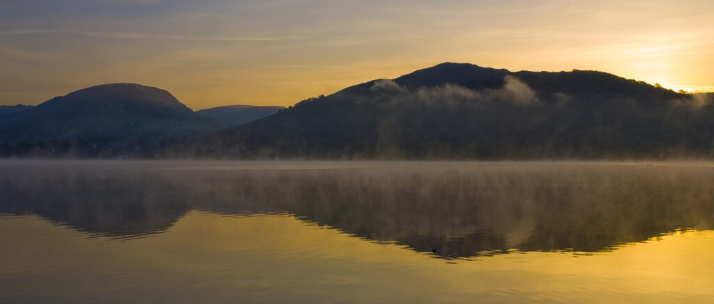 England, Cumbria, Lake District National Park. Dawn at Low Wray, looking across the still waters of Windermere, the largest lake to be found in England.