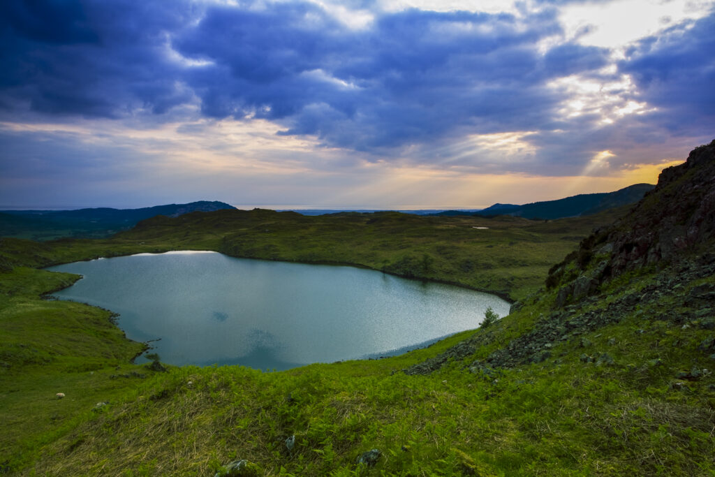 England, Cumbria, Lake District National Park. Dramatic clouds over the irish sea reflected in Blea Tarn near Boot in the Western Lake District.