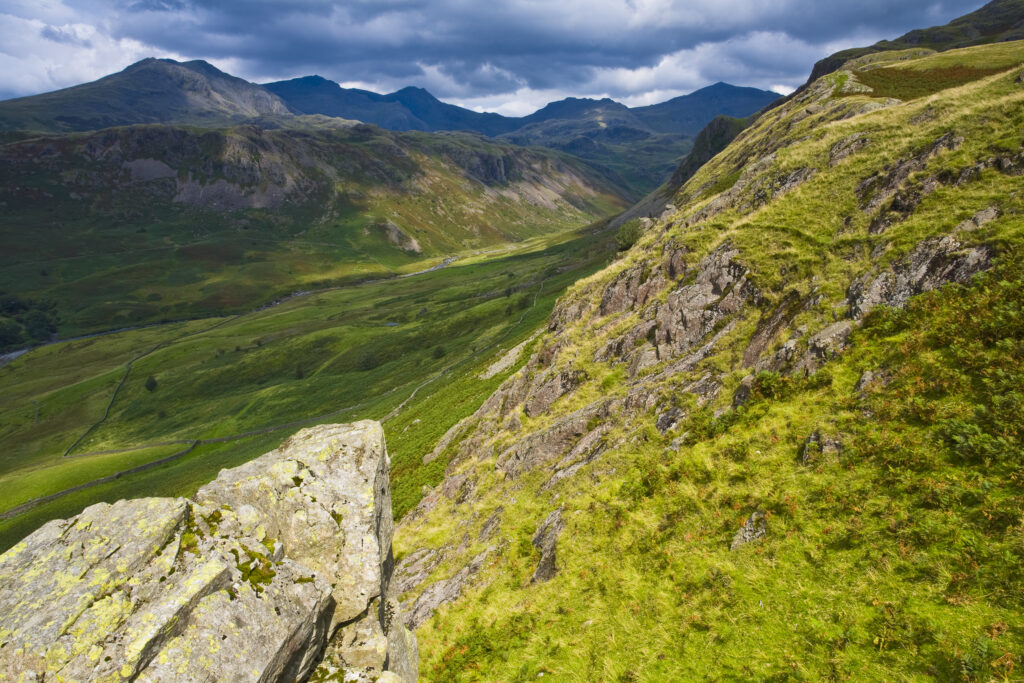 England, Cumbria, Lake District National Park. Looking along the route of the River Esk from the Hardknott Castle Roman Fort, as storms clouds gather above the countrys’ highest peak, Scafell Pike at 3205ft.
