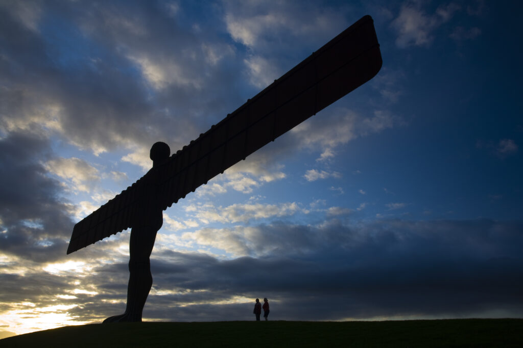 England, Tyne and Wear, Gateshead. Two tourists admire the iconic Angel of the North.