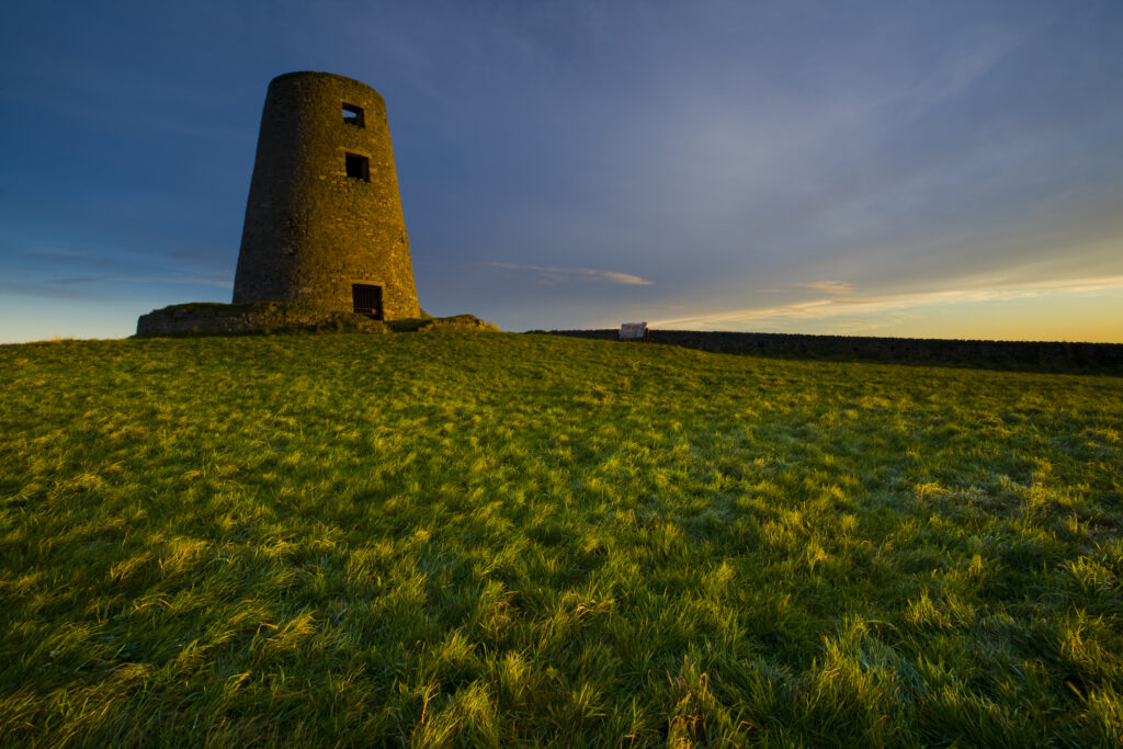 England, Tyne & Wear, Cleadon Hills. The rising sun spotlights the old mill in Windmill Field, located within the Cleadon Hills Local Nature Reserve.