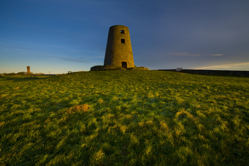 England, Tyne & Wear, Cleadon Hills. The rising sun spotlights the old mill in Windmill Field, located within the Cleadon Hills Local Nature Reserve.