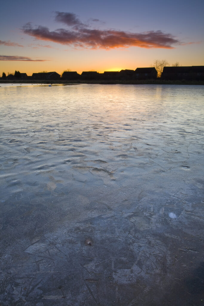England, Tyne & Wear, Killingworth. Ice covered lake near to a residential estate in Killingworth.