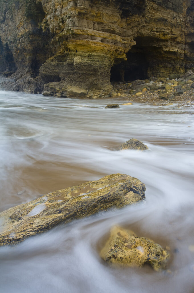 England, Tyne and Wear, Marsden. The North Sea engulfs the rocky shoreline of Marsden Bay. The sculptured form of the Marsden Rock is testament to the powerful natural forces of this often unrelenting stretch of coast.