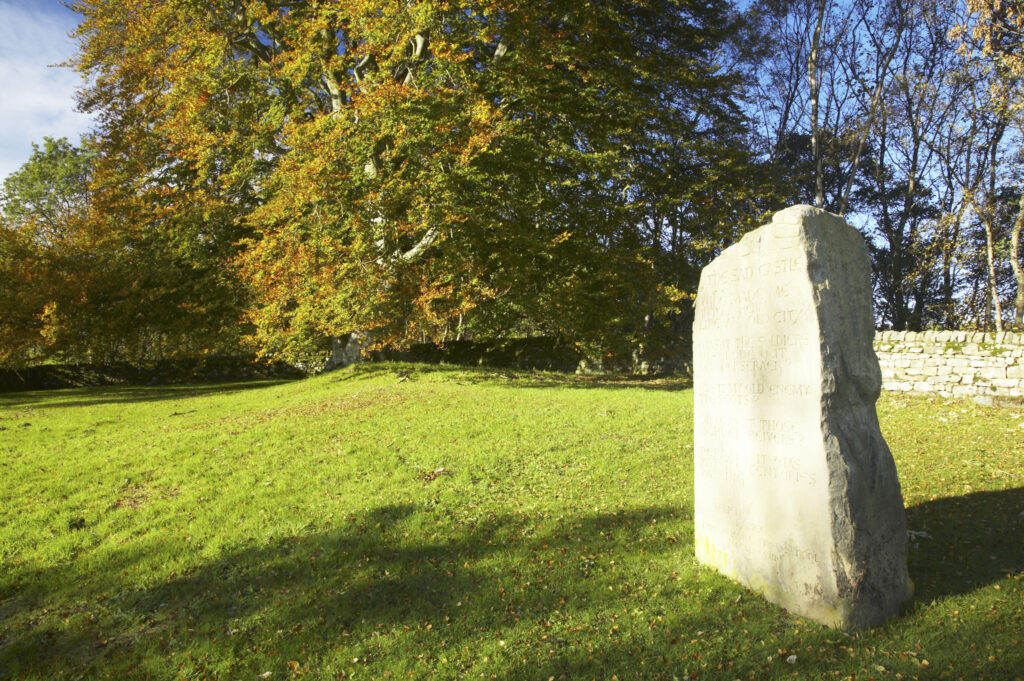 England, Northumberland, Northumberland National Park. Stone monument and autumn colours near the remains of Harbottle Castle in Coquetdale