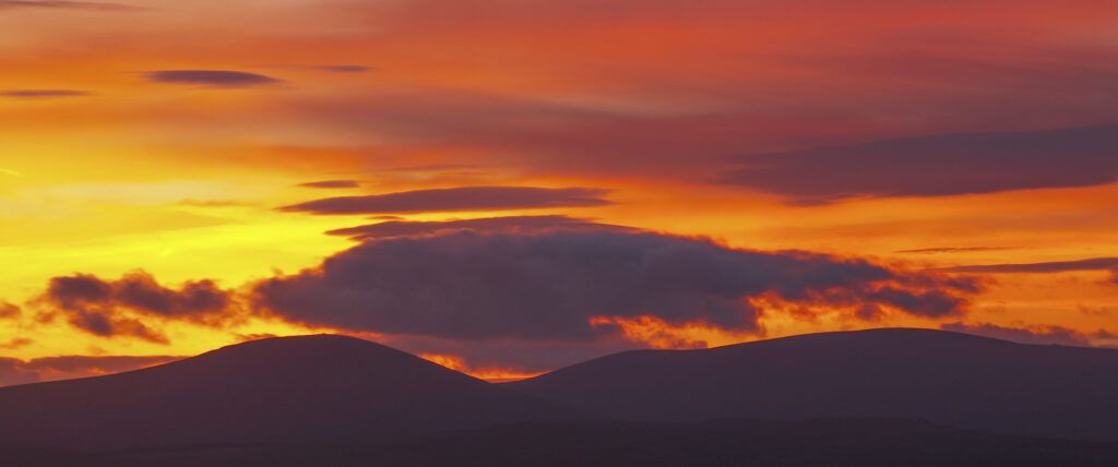 England, Northumberland, Northumberland National Park. A spectacular sunset over the Cheviot Hills, viewed from Ros Castle (National Trust)