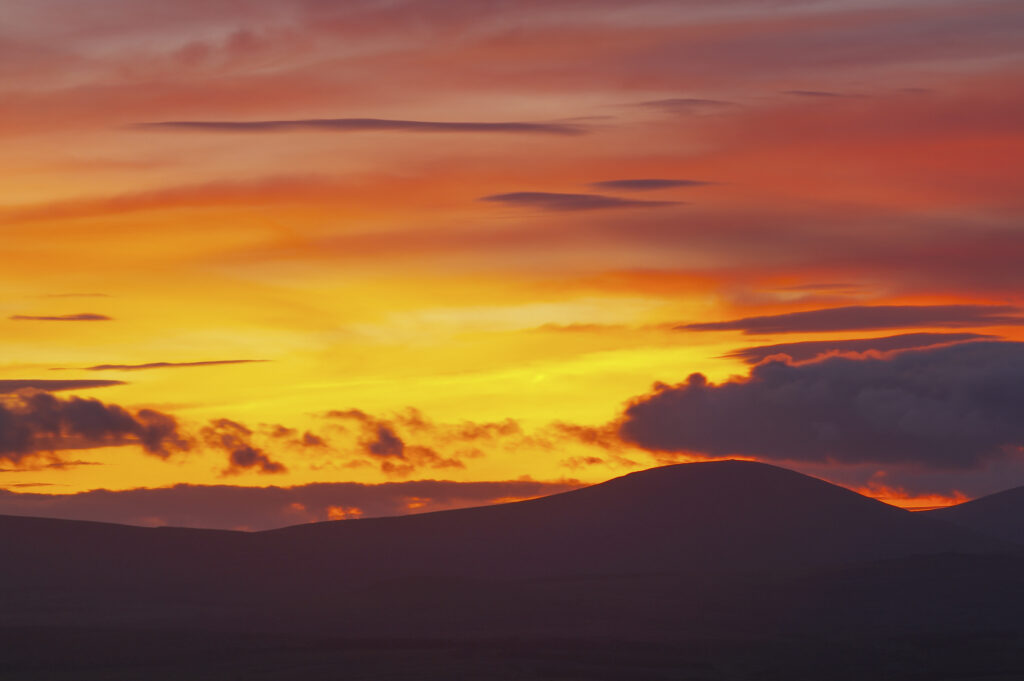 England, Northumberland, Northumberland National Park. A spectacular sunset over the Cheviot Hills, viewed from Ros Castle (National Trust)