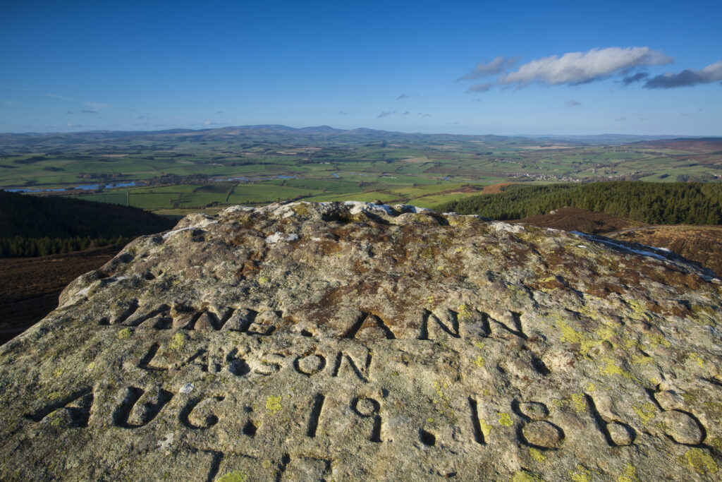 England, Northumberland, Simonside Hills. Name engraved on a side of a rock on the Simonside Hills, looking towards the Cheviot Hills and the Northumberland National Park.