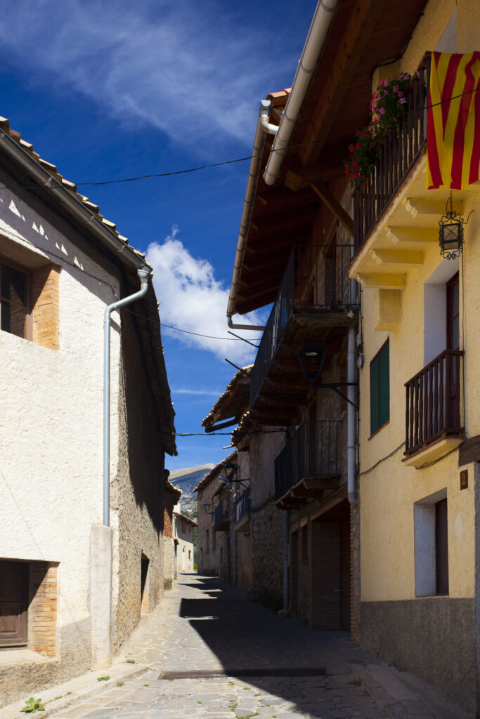 Spain, Catalonia, Pyrenees, Gósol. Catalonia flags hanging in a traditional street in the mountain village of Gósol.
