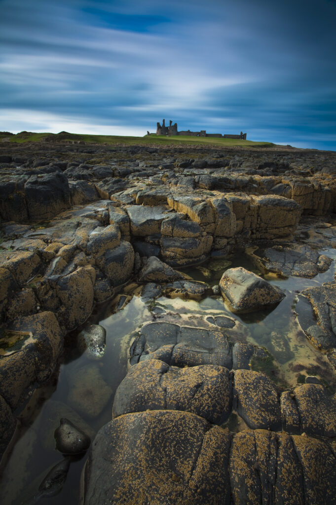 England, Northumberland, Dunstanburgh Castle. The dramatic coastline south of the enigmatic ruins of Dunstanburgh Castle.