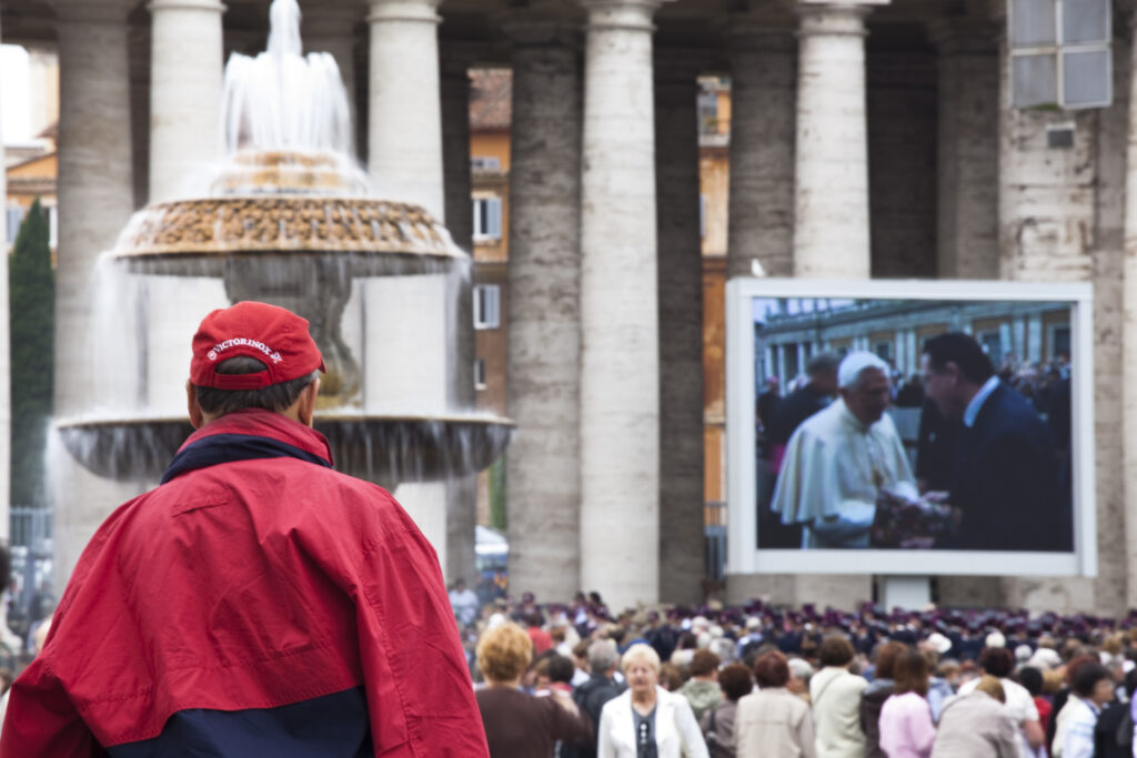 Italy, Lazio, Rome. Crowds gather to view a mass delivered by the Pope in the Piazza San Pietro and St. Peter's Basilica in Vatican City.
