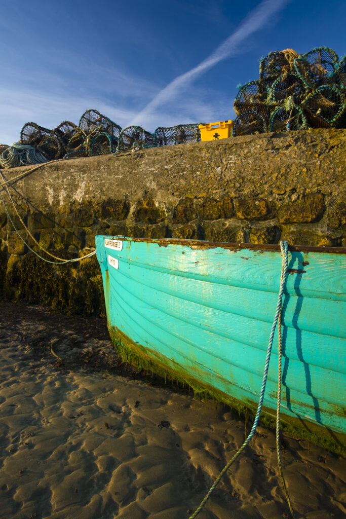 England, Northumberland, Beadnell. Boat moored within the Harbour Walls of the Beadnell Harbour - viewed at low tide.