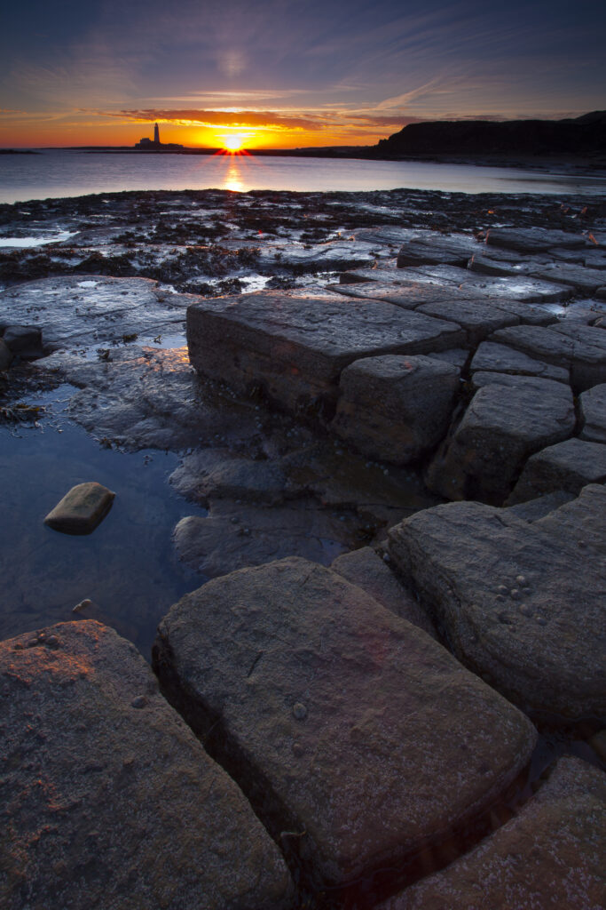 England, Tyne and Wear, Whitley Bay. Looking from bay north of Whitley Bay towards St Mary's Lighthouse and Island at sunrise.