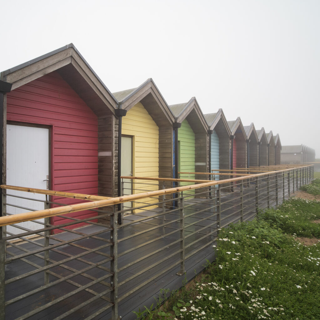 England, Northumberland, Blyth. Colourful Beach Huts located on South Blyth Sea Front, photographed on a foggy morning.