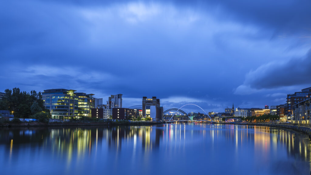 England, Tyne and Wear, Newcastle Upon Tyne. Dusk voew of The Gateshead Millennium Bridge, Tyne Bridge and Baltic Building located alongside the River Tyne and Newcastle / Gatehead Quayside