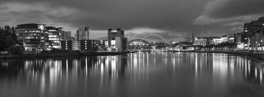England, Tyne and Wear, Newcastle Upon Tyne. Dusk voew of The Gateshead Millennium Bridge, Tyne Bridge and Baltic Building located alongside the River Tyne and Newcastle / Gatehead Quayside