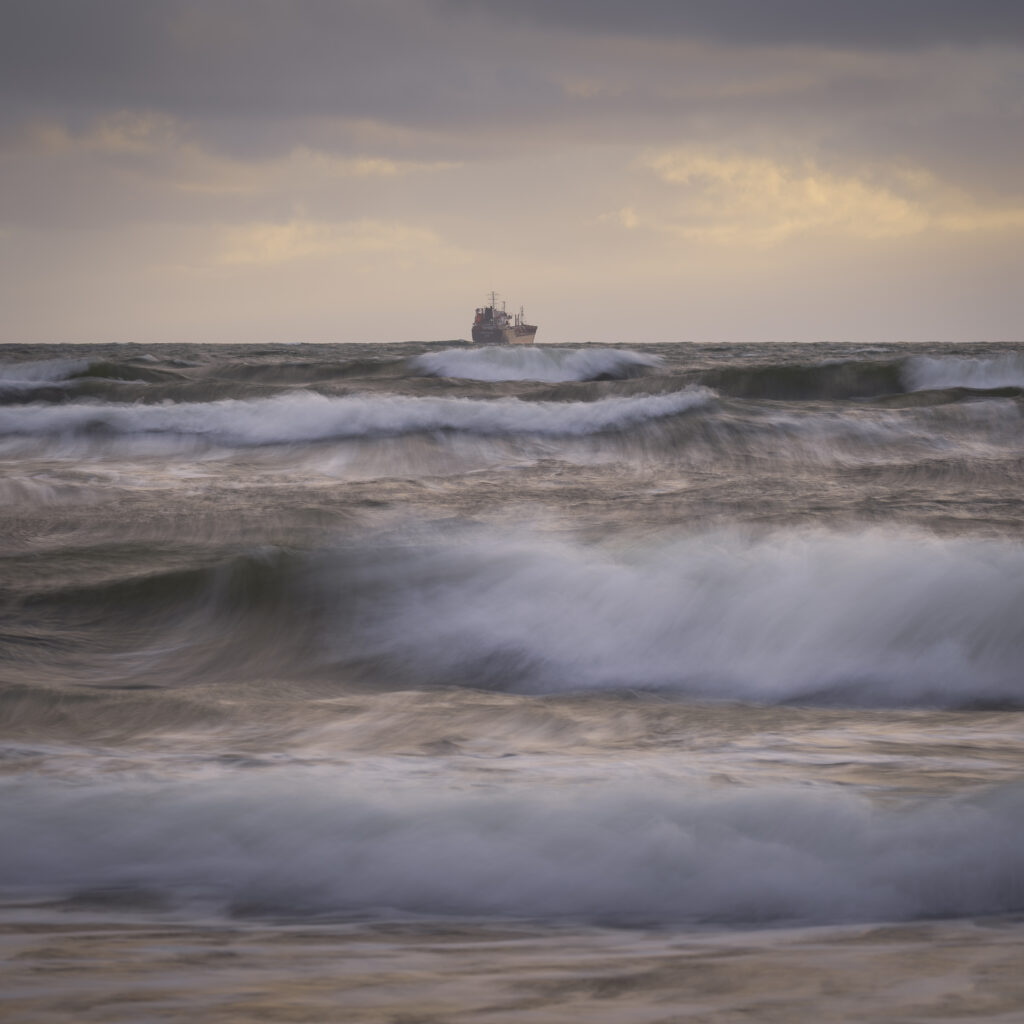 England, Tyne and Wear, Tynemouth. A shipping boat on the north sea photographed on a gusty morning at sunrise.