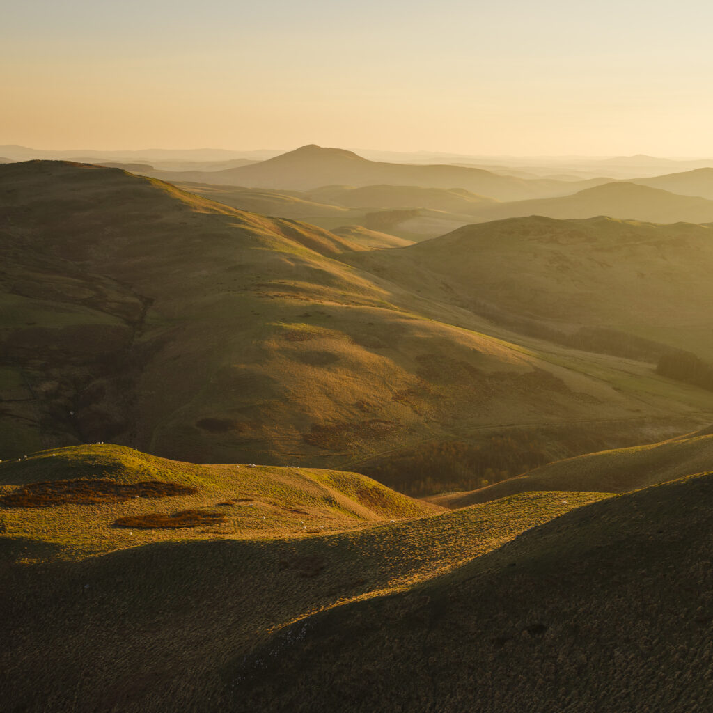 Scotland, Scottish Borders, Kirk Yetholm. View from the Pennine Way near White Law in Northumberland, looking towards Wildgoose Hill, Latchly Hill, the Southern Uplands and the Eildon Hills in the Scottish Borders, on a misty evening at sunset.