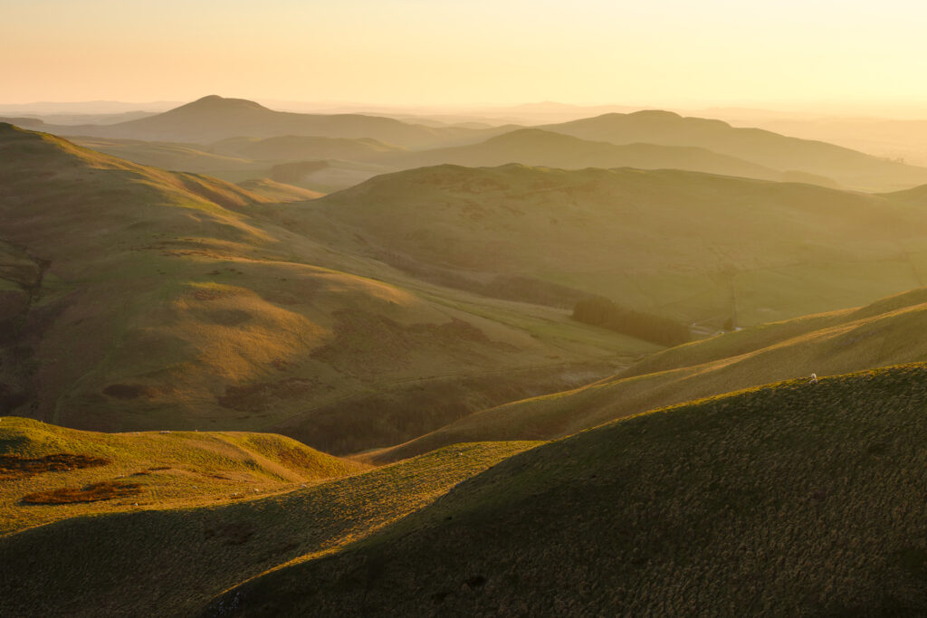 Scotland, Scottish Borders, Kirk Yetholm. View from the Pennine Way near White Law in Northumberland, looking towards Wildgoose Hill, Latchly Hill, the Southern Uplands and the Eildon Hills in the Scottish Borders, on a misty evening at sunset.