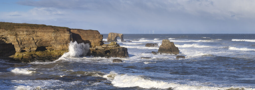 England, Tyne and Wear, Marsden Bay. Morning autumnal light illuminates the crashing waves of the North Sea, near Lizard Point and Marsden Bay.