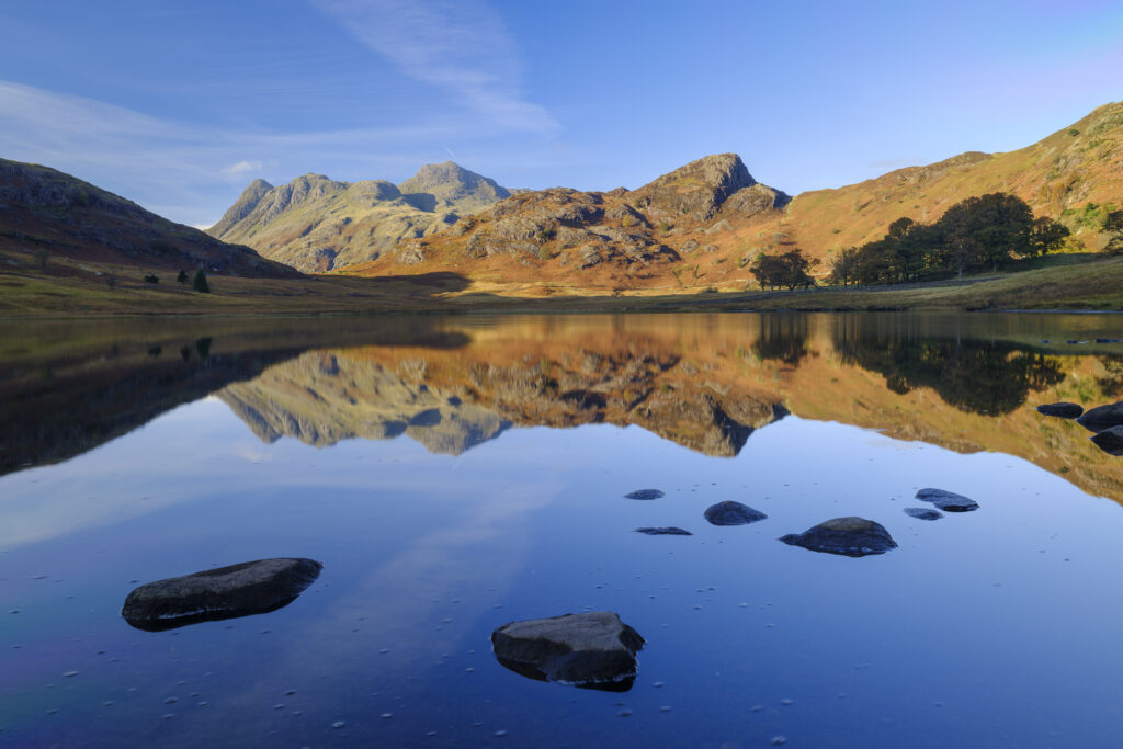 England, Cumbria, Lake District National Park. The Langdale Mountains reflected on the calm waters of Blea Tarn.